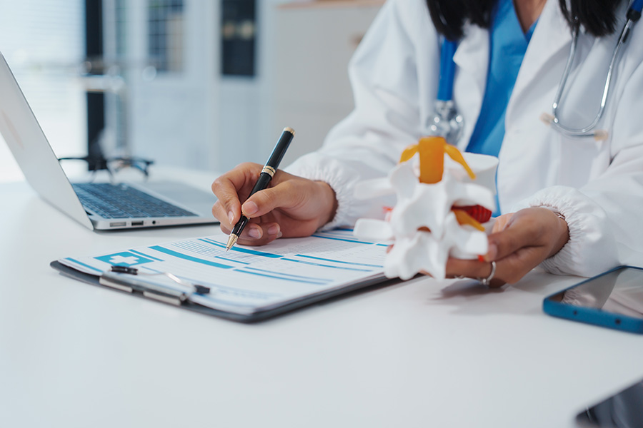 Asian female doctor uses a model of a lumbar disc to work with a
